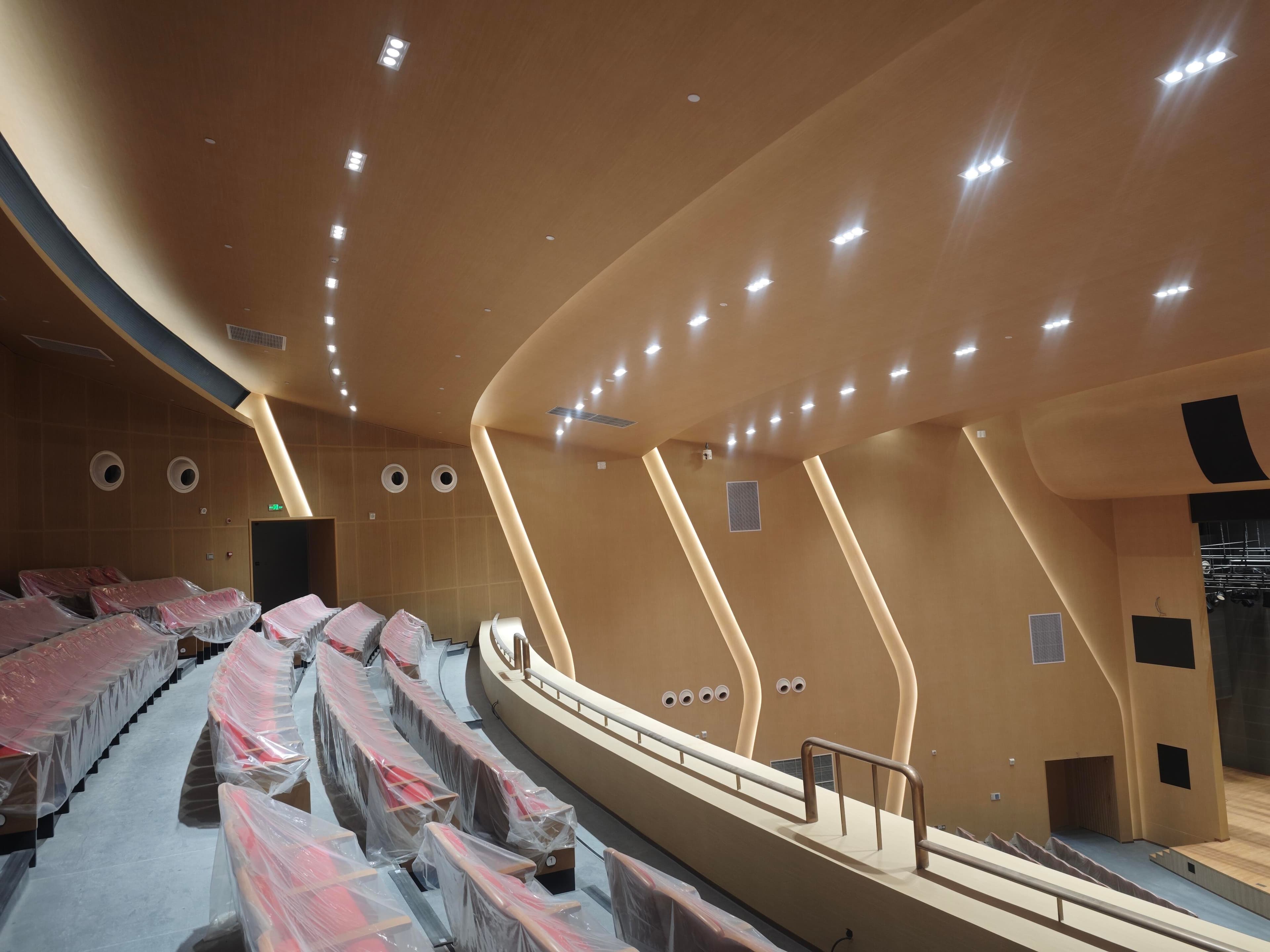 Upper balcony auditorium view showing seating rake, side-wall acoustic geometry, and stage opening