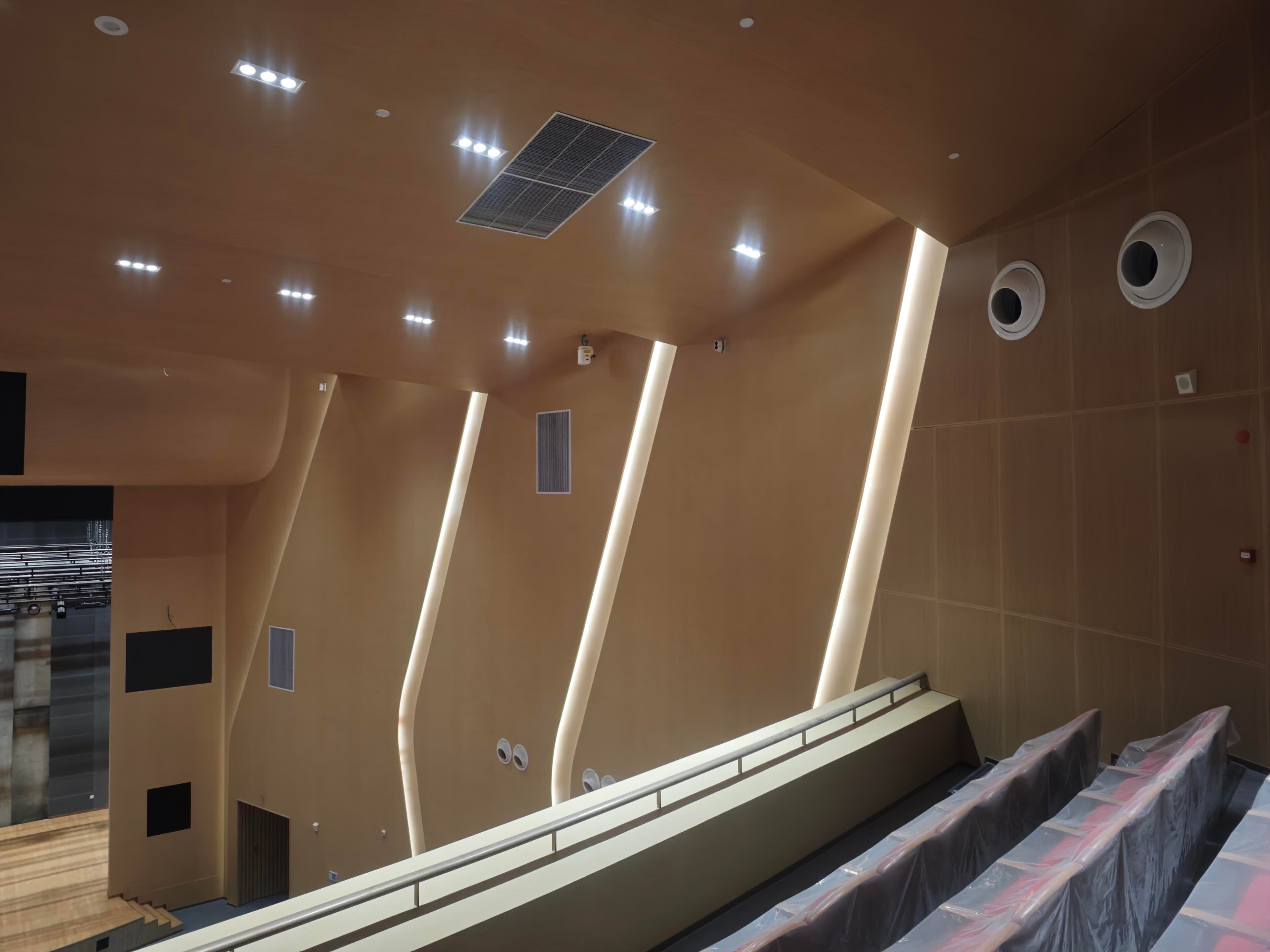 Upper auditorium side wall and ceiling detail with perforated panels, air outlets, and concealed light slots