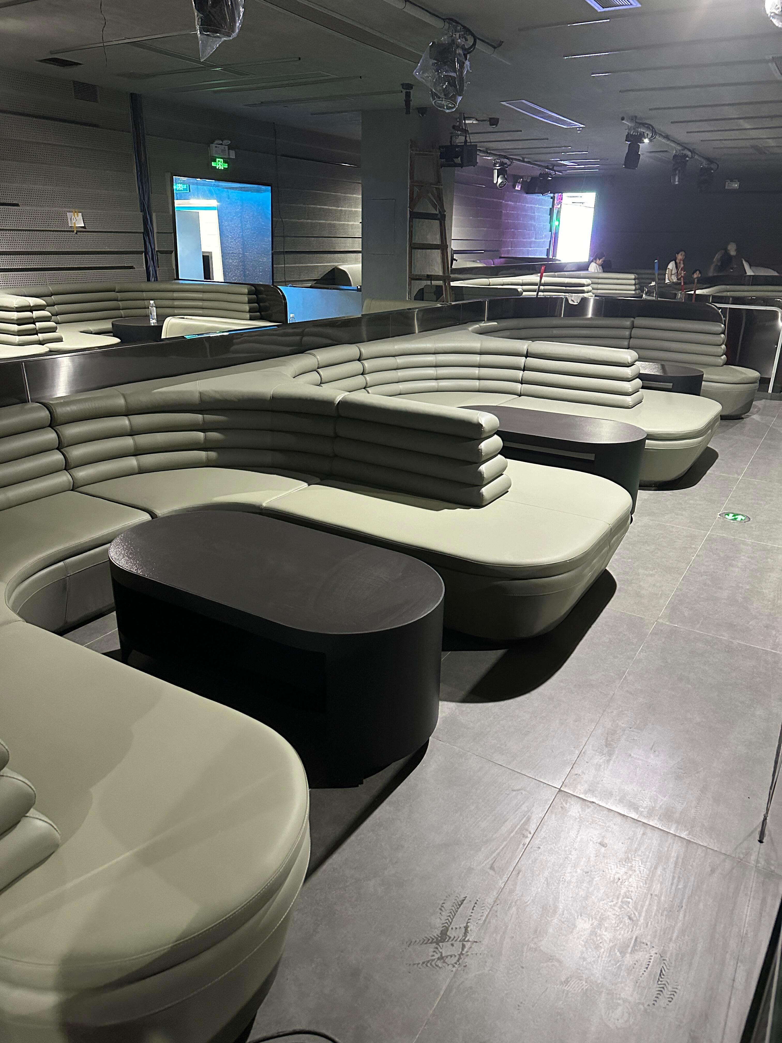 XIANG LIVESHOW tiered booth seating with streamlined leather sofas and matte black tables