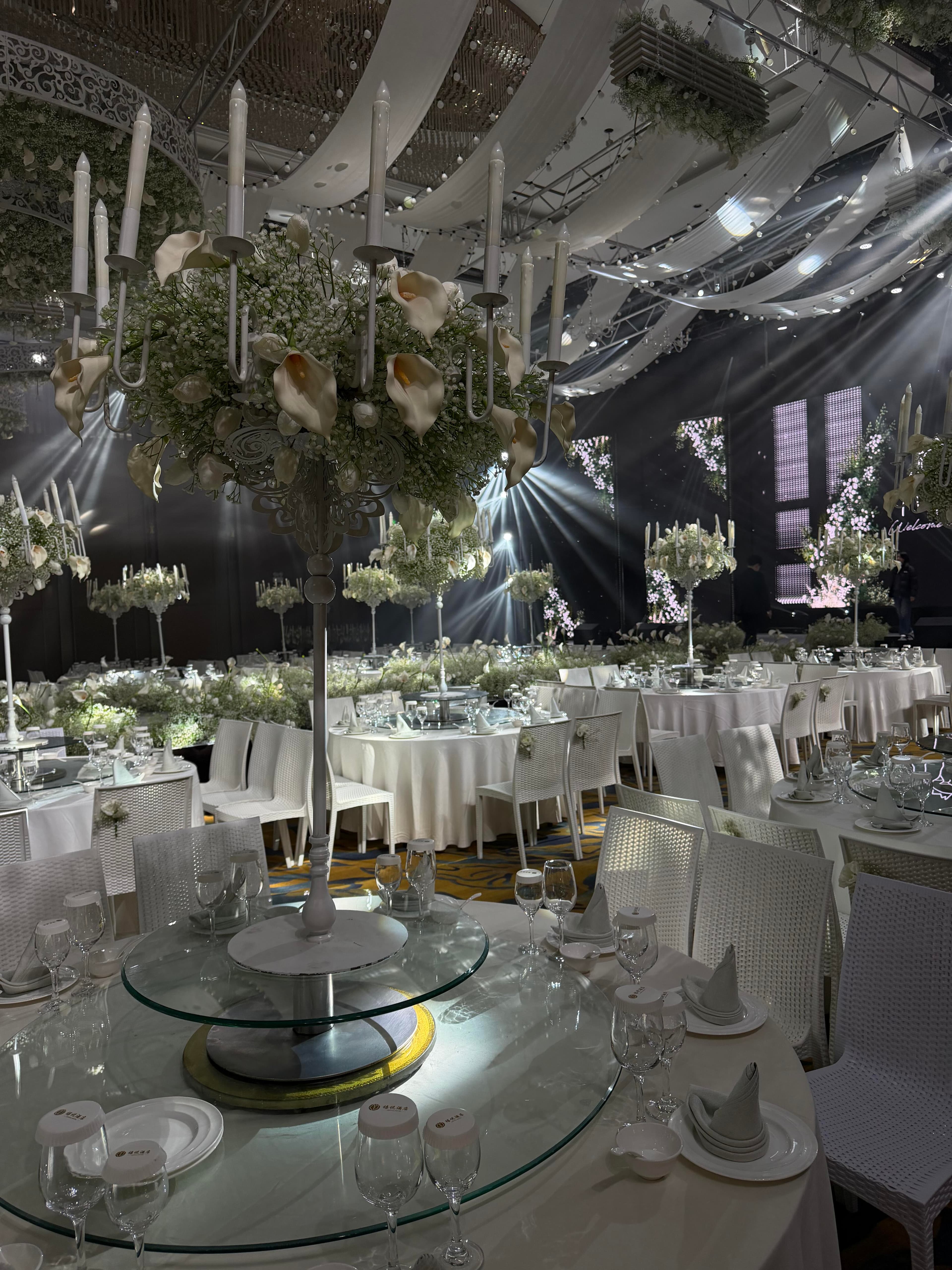 Local ballroom view showing wave-shaped drapes, floral ceiling arrays, and low-profile stage lighting