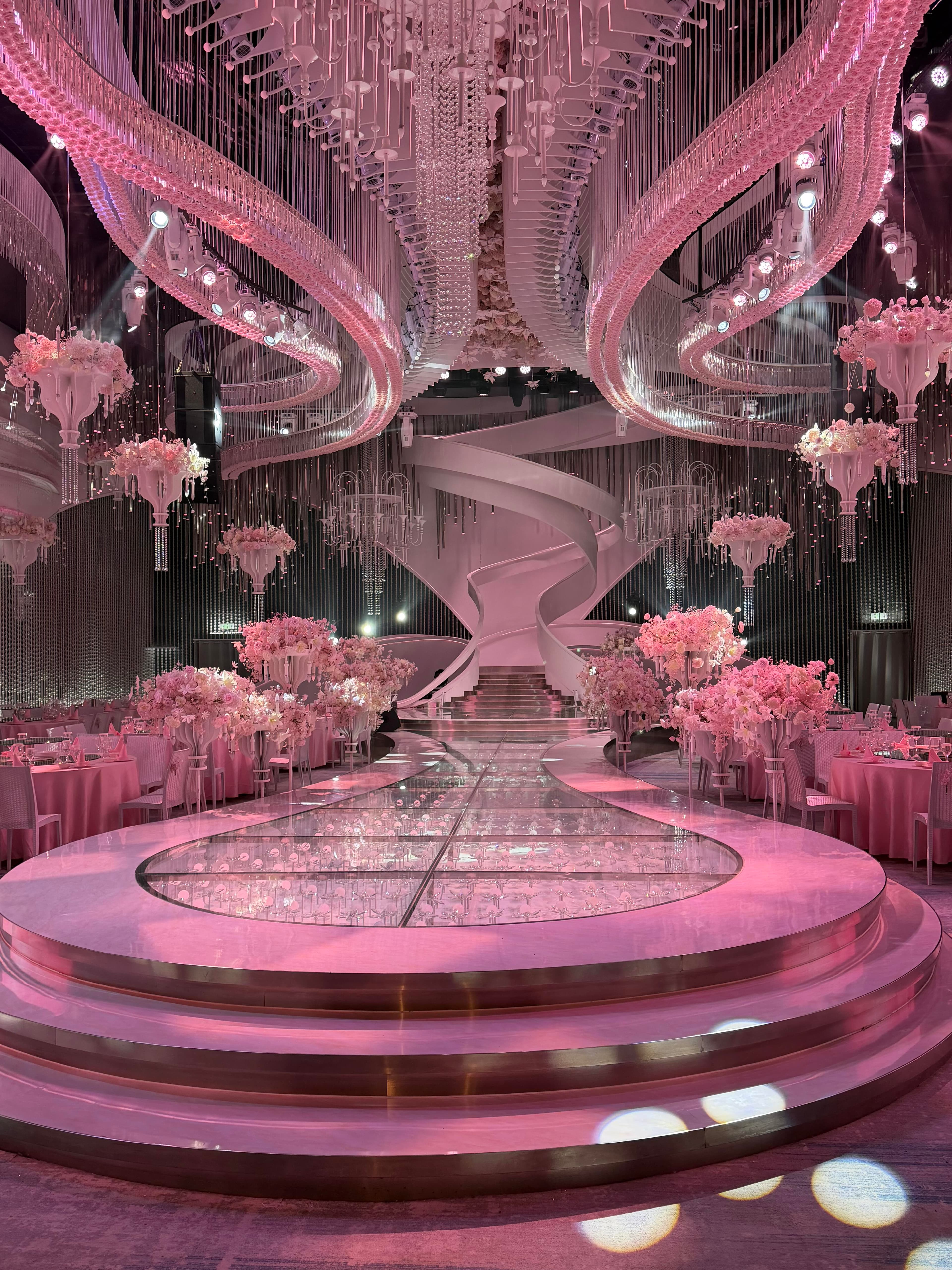 Pink themed ballroom with dual-curvature ceiling installation and suspended light fixtures