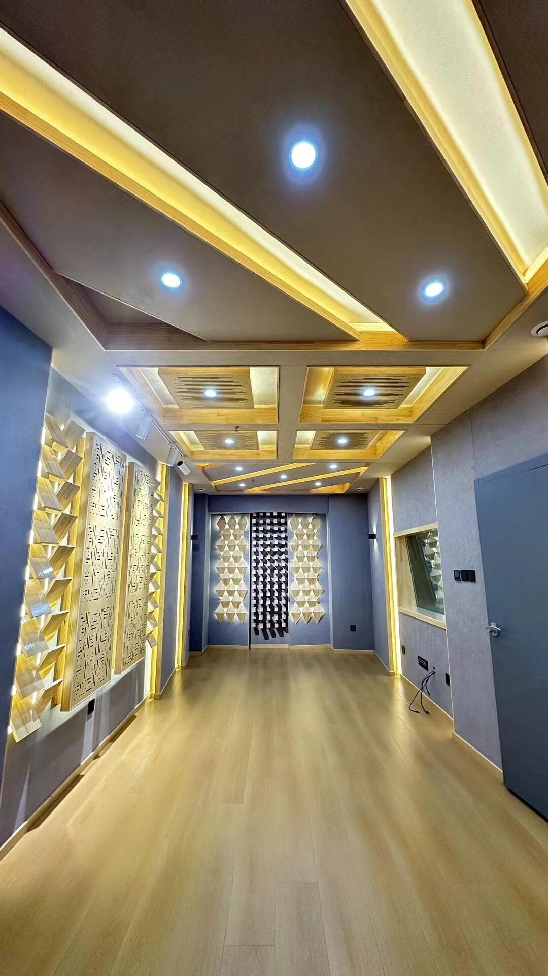 Long empty recording room with triangular diffuser arrays and floating acoustic ceiling panels