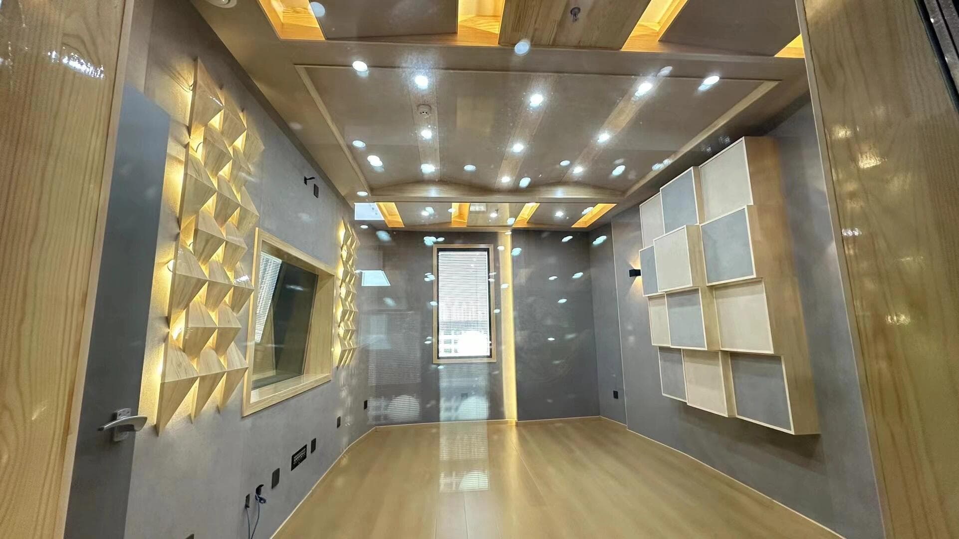 Empty recording room viewed through glass with observation window and staggered wall acoustic modules
