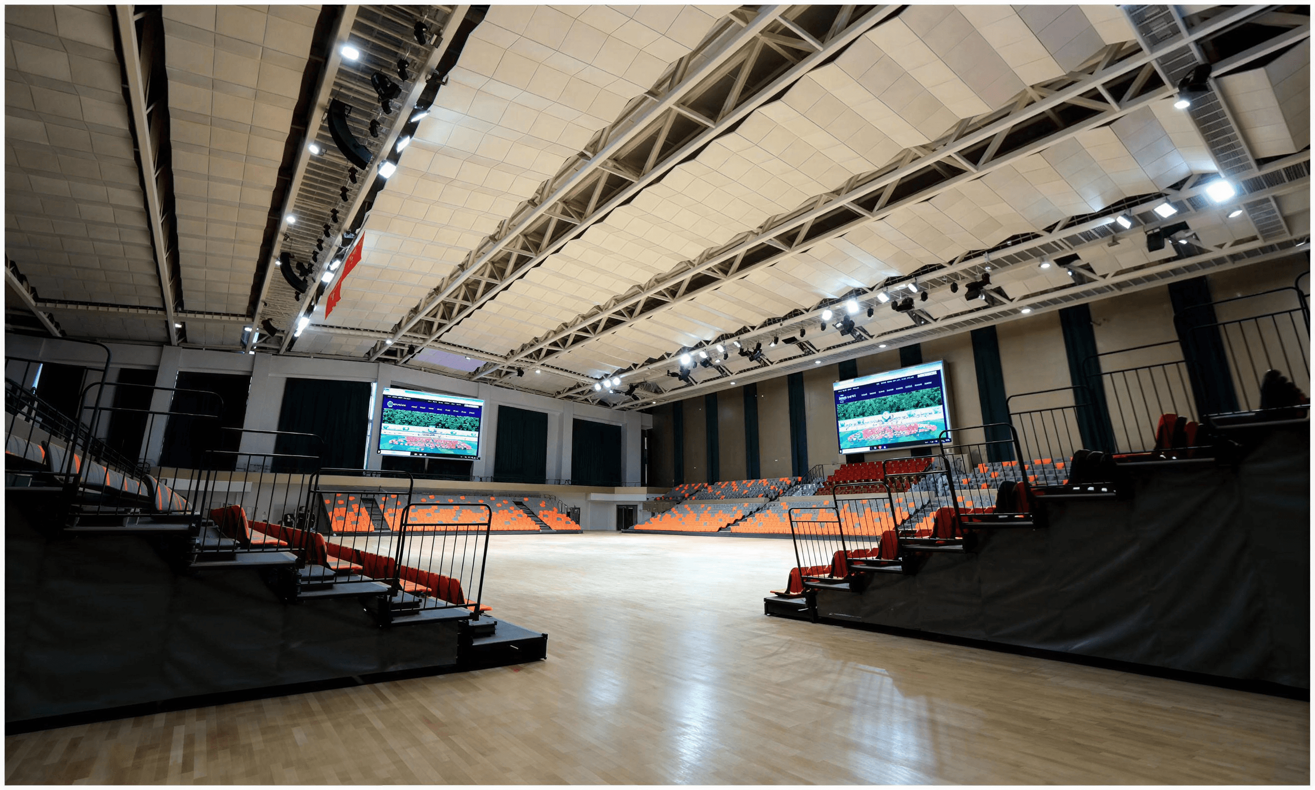 View from mid-court facing the main stage and screen with ceiling absorption matrix and seating