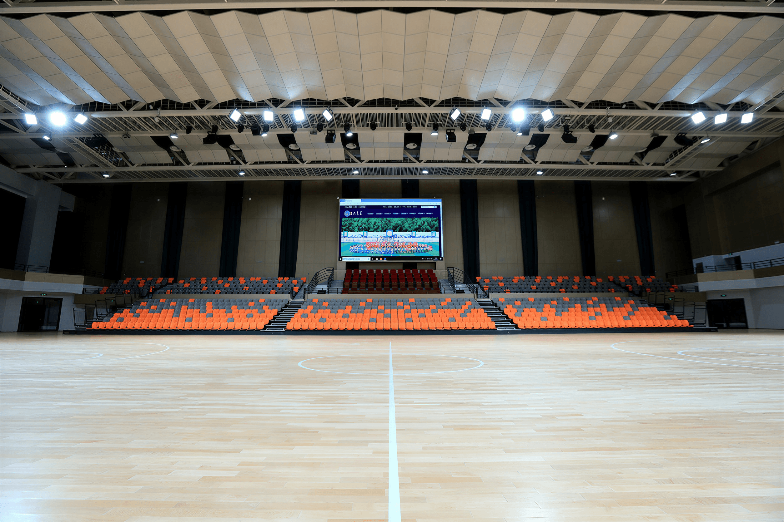 Elevated view from the upper tier showing three-screen display system and suspended line array clusters