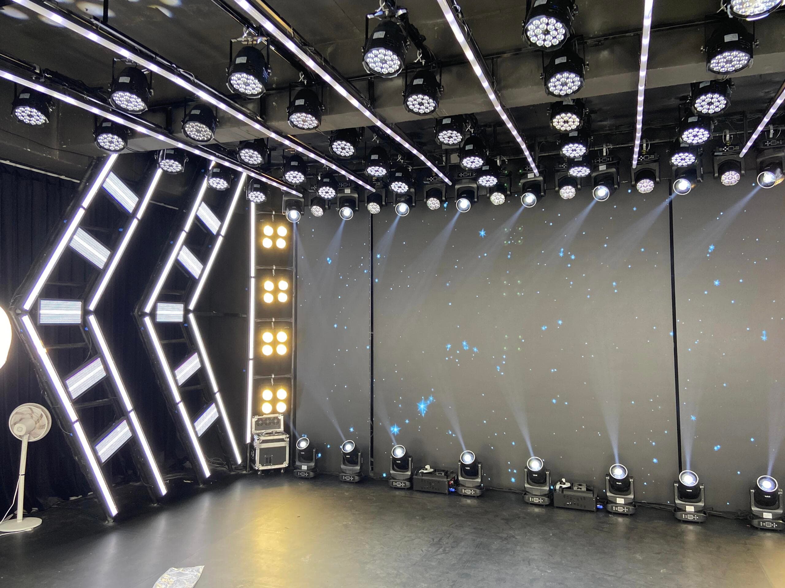 Geometric arrow-shaped truss lighting and overhead matrix in the broadcast studio