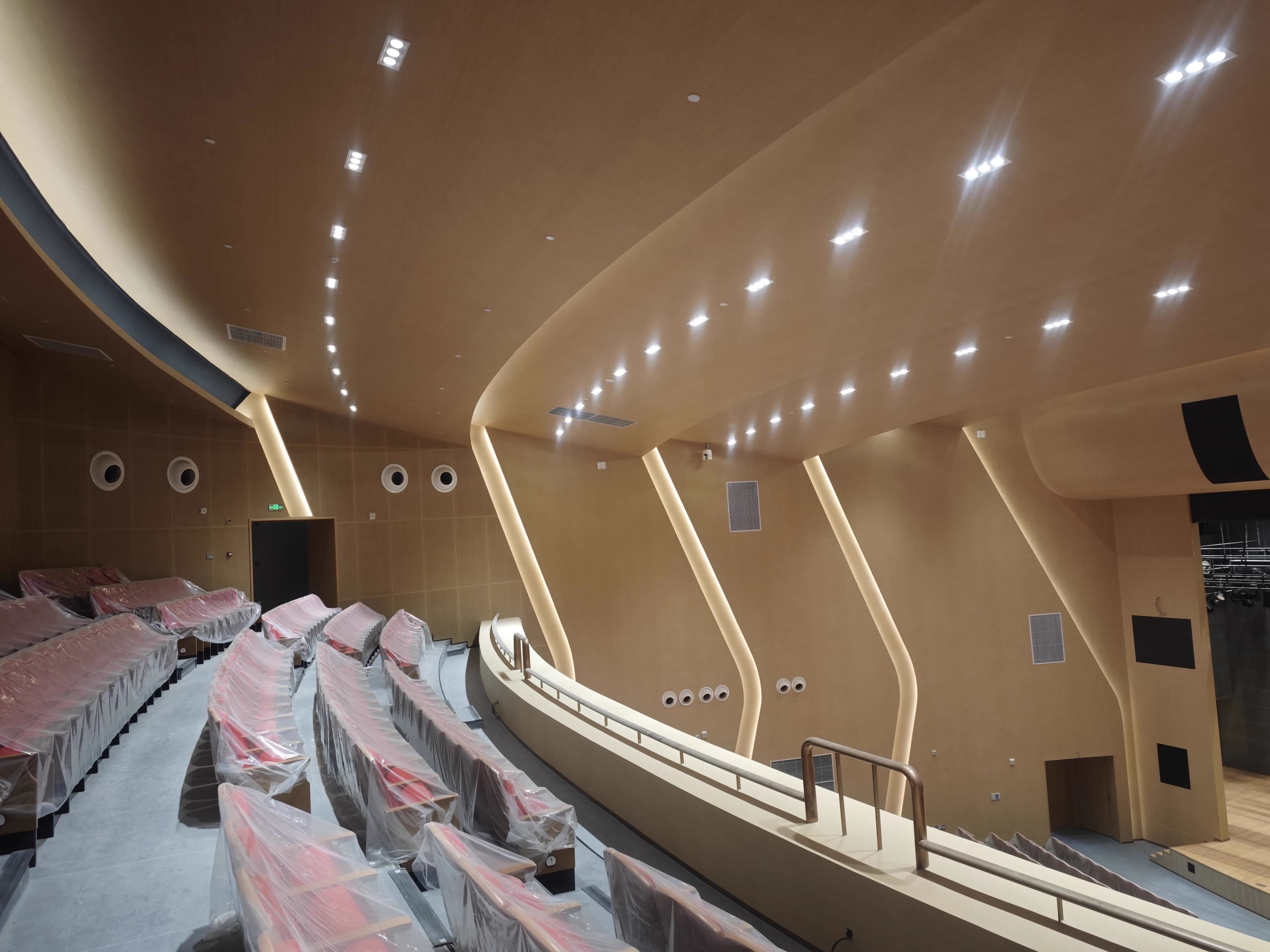 Upper balcony auditorium view showing seating rake, side-wall acoustic geometry, and stage opening