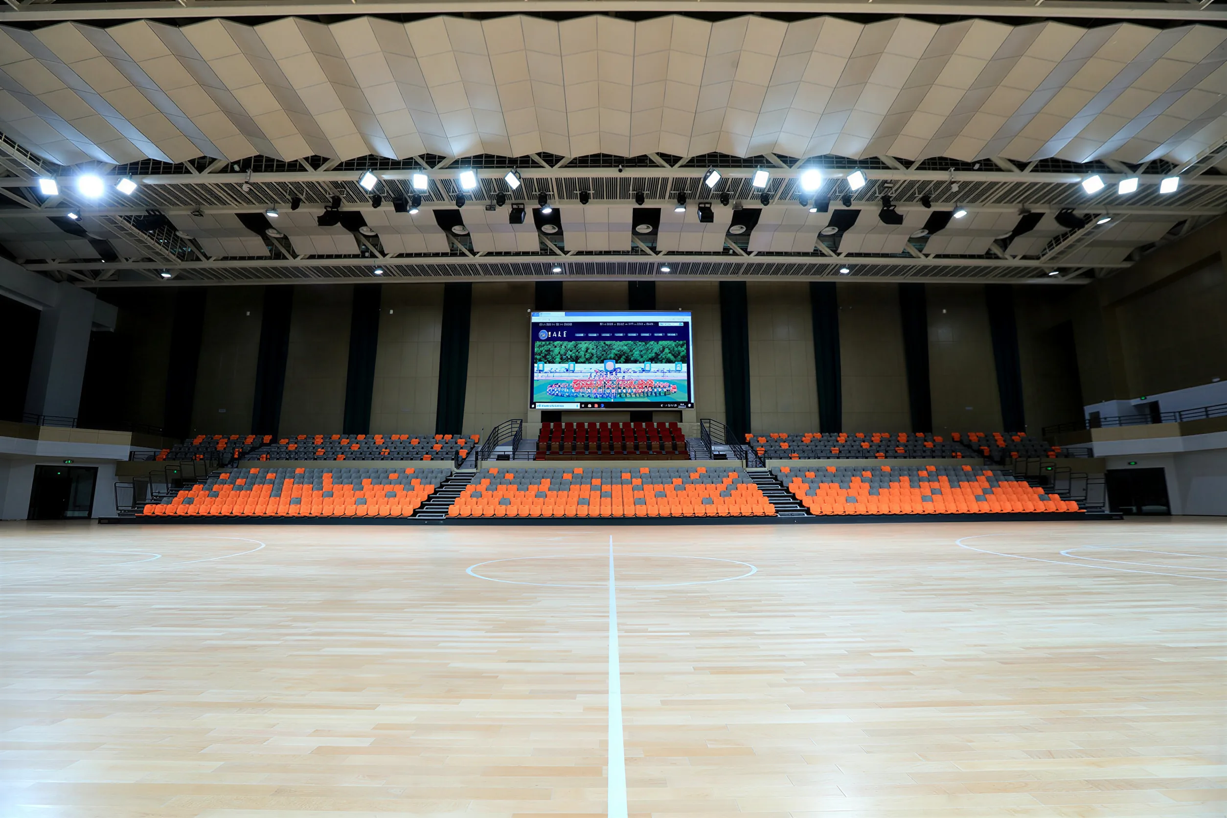Elevated view from the upper tier showing three-screen display system and suspended line array clusters